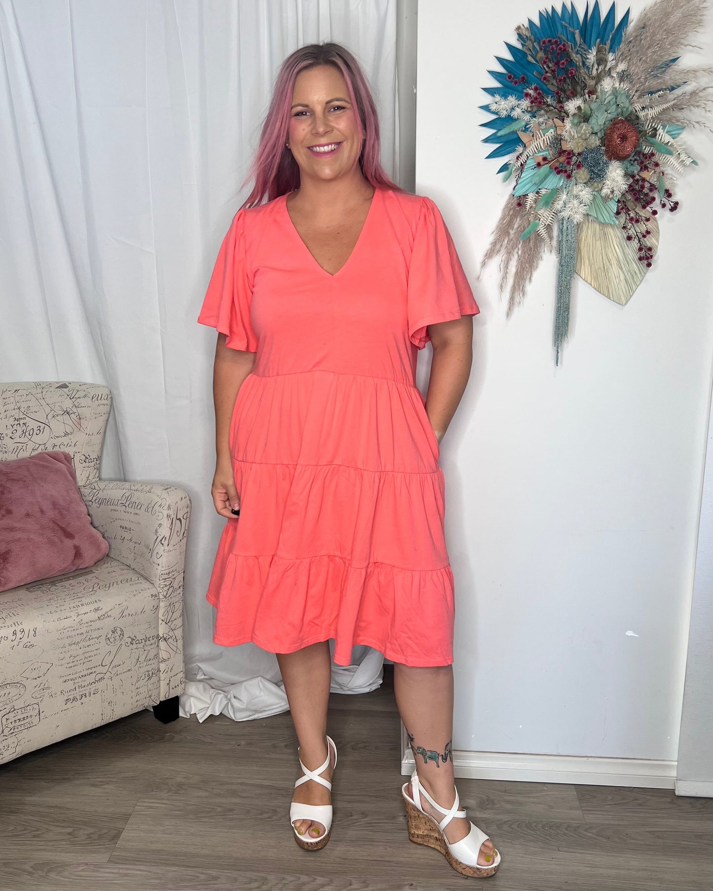 Cressida Dress - Coral | Betty Basics | Introducing the Cressida Dress your carefree chic essential! With a V-neck, flutter sleeves, a relaxed tiered body, and pockets for added flair, this dress effortles