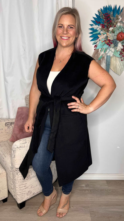 Alica Belted Sleeveless Coat - Black | Betty Basics | Are you ready to add a touch of elegance to your autumnal layering game? Look no further than the Alicia Belted Sleeveless Coat! This piece is the perfect combinatio