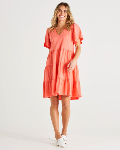 Cressida Dress - Coral | Betty Basics | Introducing the Cressida Dress your carefree chic essential! With a V-neck, flutter sleeves, a relaxed tiered body, and pockets for added flair, this dress effortles