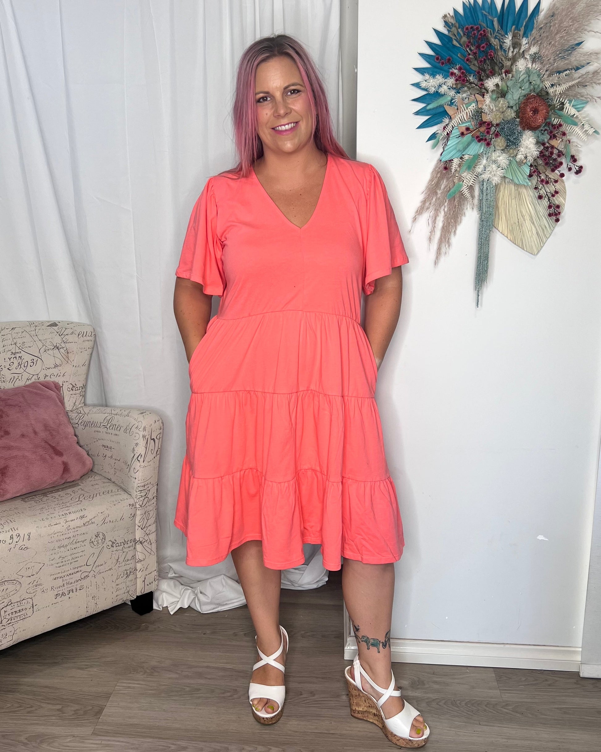 Cressida Dress - Coral | Betty Basics | Introducing the Cressida Dress your carefree chic essential! With a V-neck, flutter sleeves, a relaxed tiered body, and pockets for added flair, this dress effortles