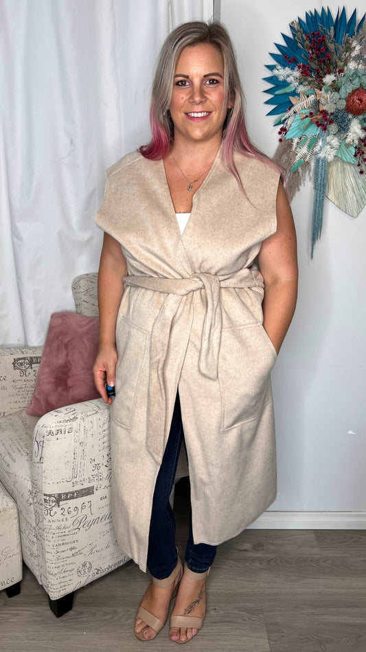 Alica Belted Sleeveless Coat - Beige | Betty Basics | Are you ready to add a touch of elegance to your autumnal layering game? Look no further than the Alicia Belted Sleeveless Coat! This piece is the perfect combinatio