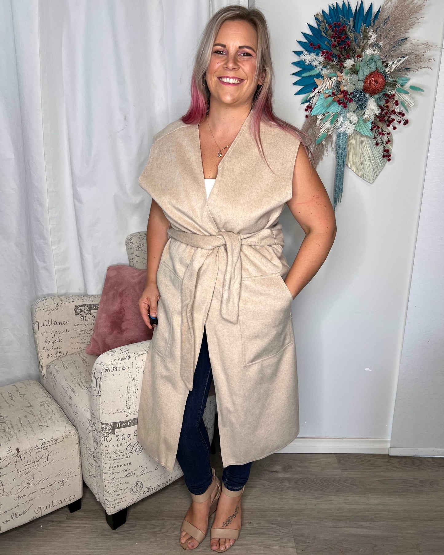 Alica Belted Sleeveless Coat - Beige | Betty Basics | Are you ready to add a touch of elegance to your autumnal layering game? Look no further than the Alicia Belted Sleeveless Coat! This piece is the perfect combinatio